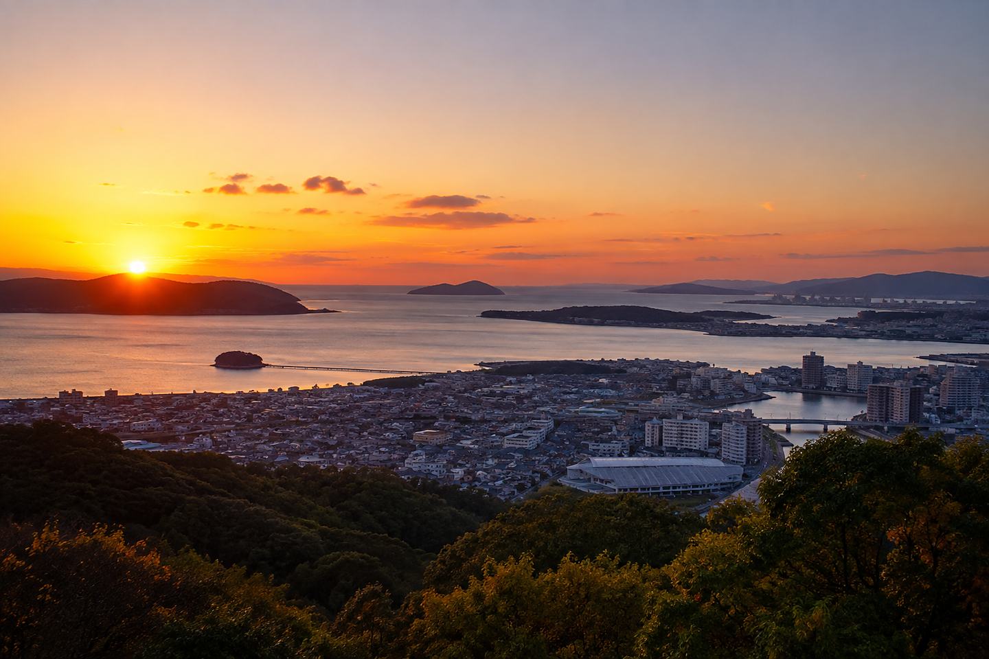 三河湾に沈む夕日と蒲郡の街並み